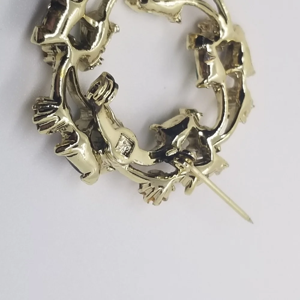 gold tone wreath brooch with clear green and black accents